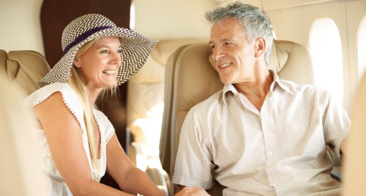 Smiling couple in their 60s talking in the cabin of a private jet